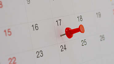Foto einer roten Pinnadel auf einem Kalender.